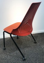Enkel stablestol på hjul, sete i rødt stoff, rygg i rød plast, sort metallunderstell, brukt med slitasje/smuss