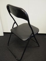 Enkel klappstol i sort kunstskinn / sortlakkert metall, pent brukt