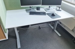 Lekkert skrivebord 160x80cm, elektrisk hevsenk, hvit bordplate / grått understell fra Holmris, pent brukt