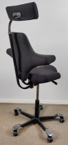 Ergonomisk kontorstol: Håg Capisco 8107 i sort stoff, sort fotkryss, 69cm sittehøyde, nakkepute, NYTRUKKET, pent brukt