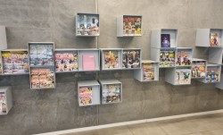 Vegghengt hylle i grålakkert metall, skråstilt display-luke med oppbevaring inni, pent brukt